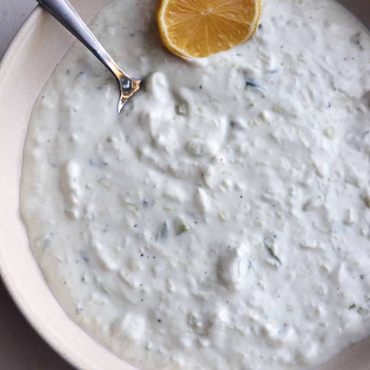 tzatziki sauce in a low bowl garnished with a lemon
