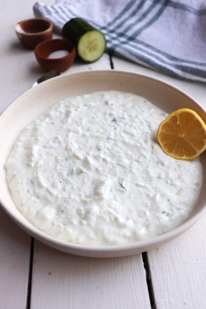 completed greek tzatziki sauce with ingredients in the background