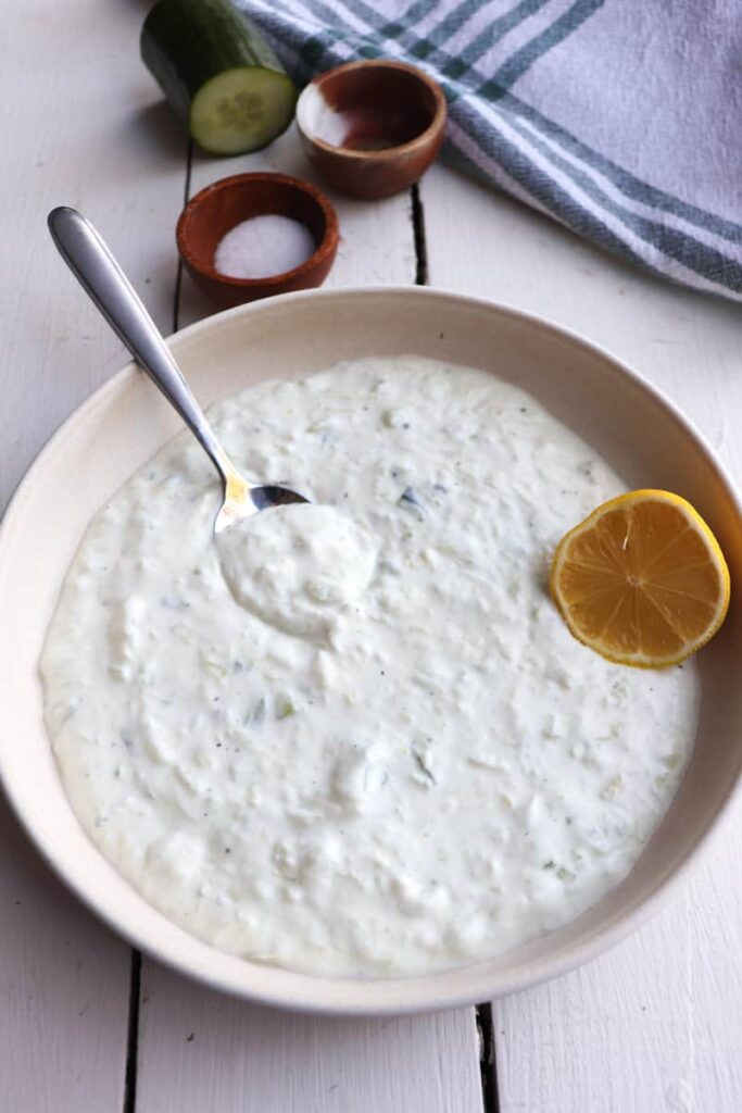completed greek tzatziki sauce with ingredients in the background