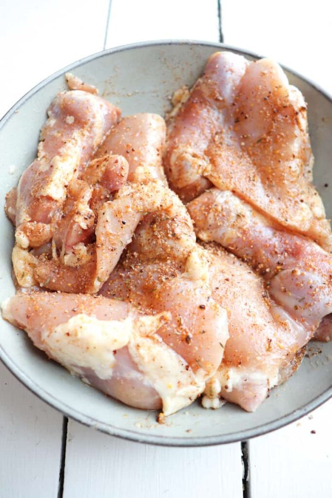 raw chicken thighs coated in seasoning