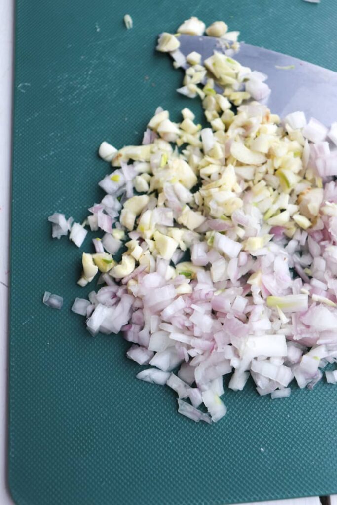 shallots and garlic minced on a green cutting board