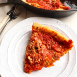 one slice of cast iron pizza on a plate with the remaining in the background