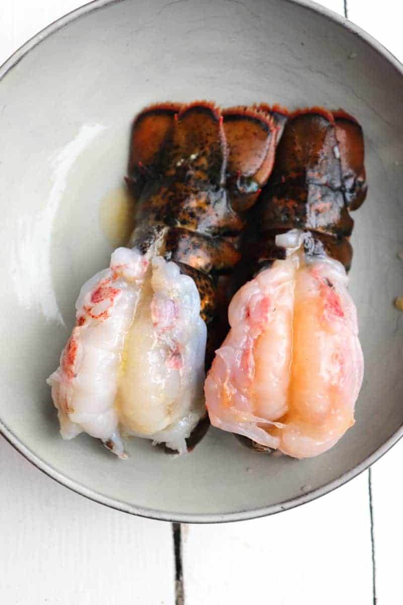raw butterflied lobster tails on a grey plate