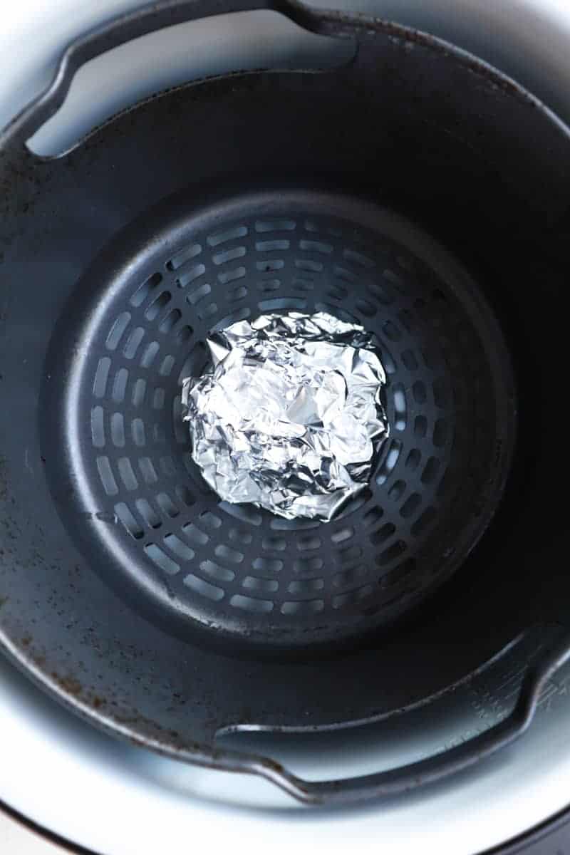 garlic bulb wrapped in foil in air fryer basket