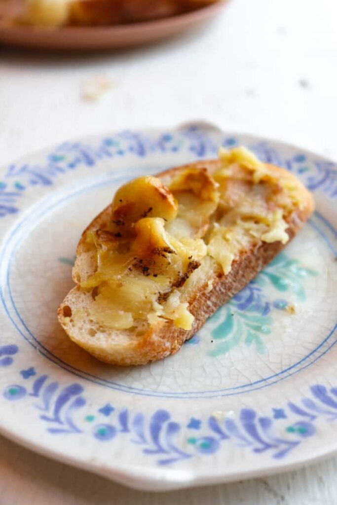 one thin slice of toast with roasted garlic spread on top