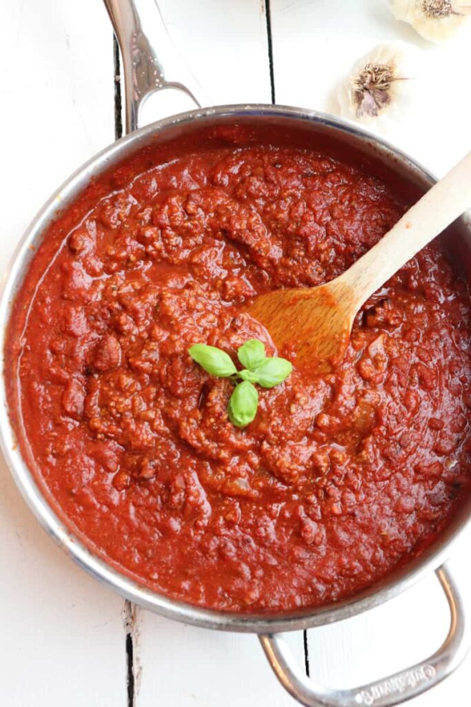 finished meat sauce in a skillet with basil for garnish