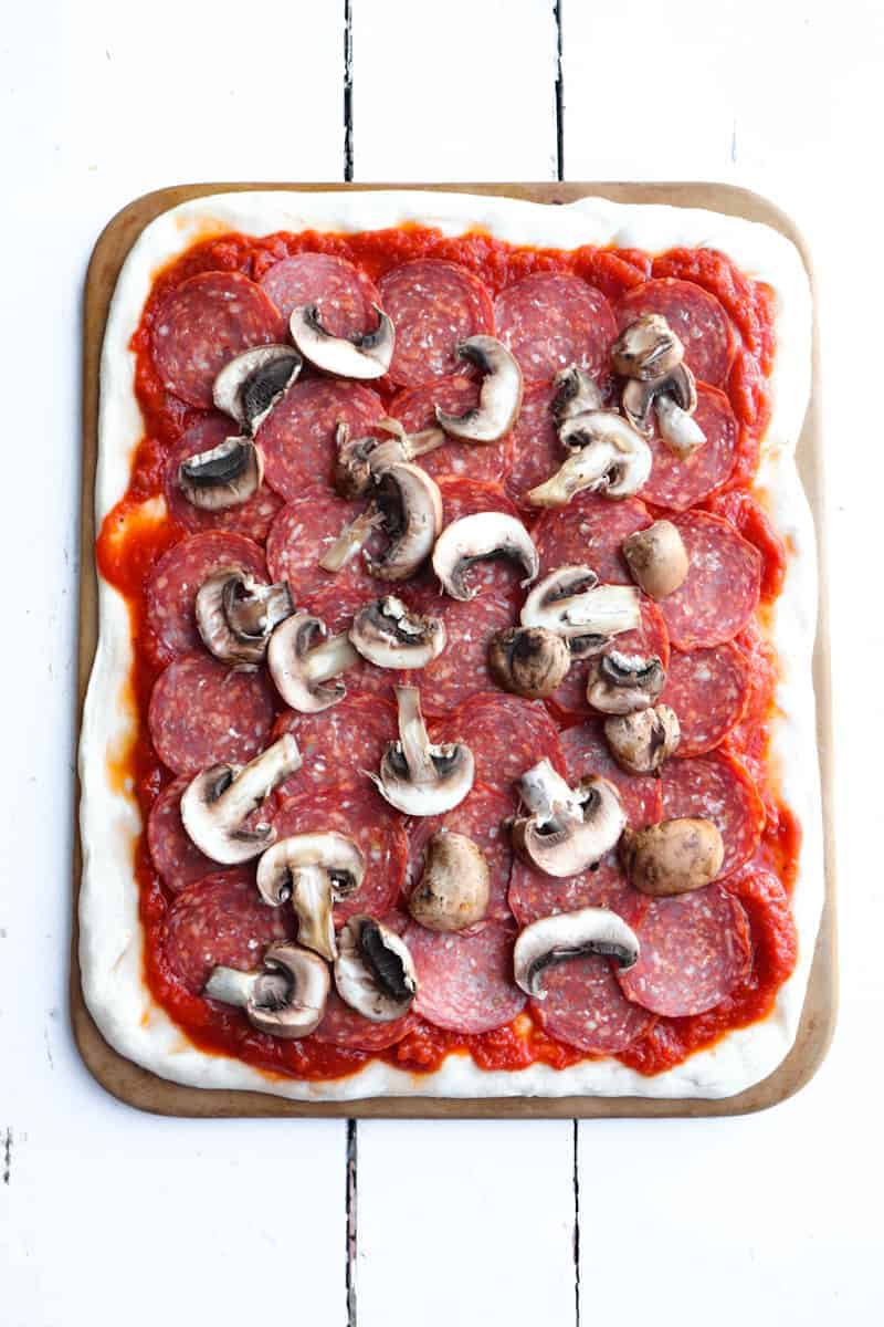 pepperoni and mushrooms on a rectangle pizza dough