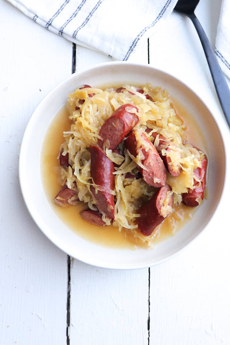 kielbasa and sauerkraut on a light colored plate.