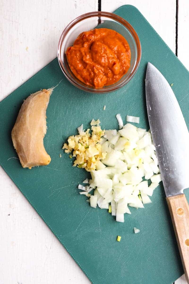 garlic, tomato, garlic, and curry paste on a green cutting board