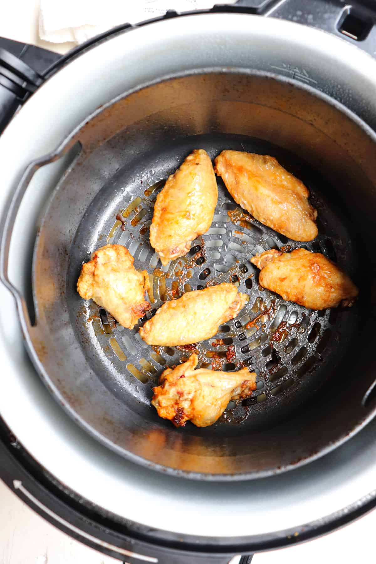 finished wings cooked from frozen in air fryer basket.