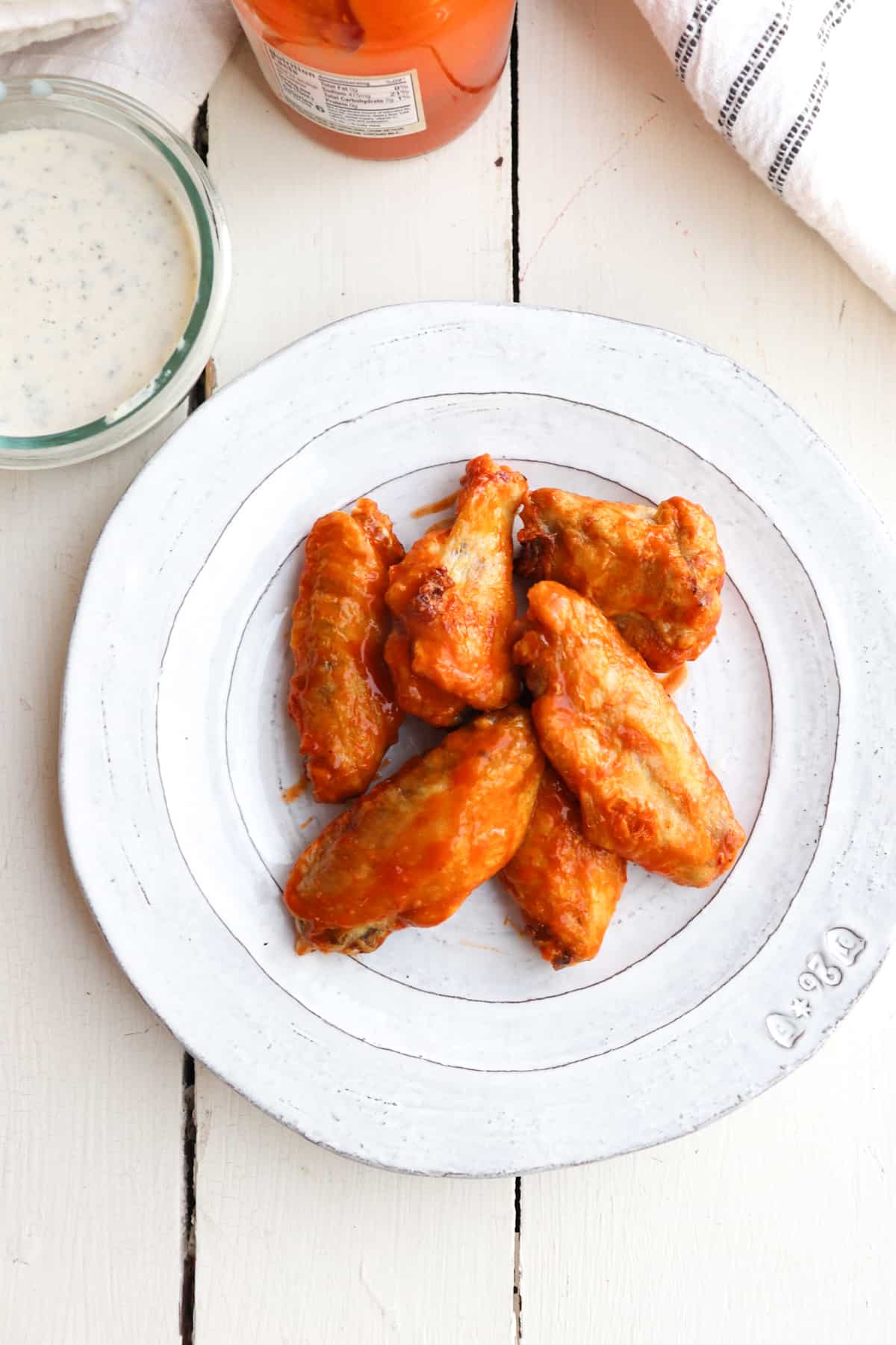 wings on a plate with ranch and buffalo sauce to the side.