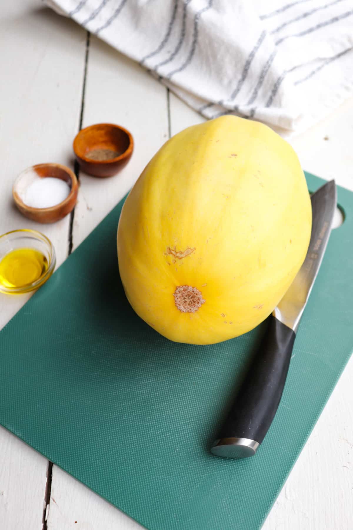spaghetti squash and seasoning ingredients on a white table.