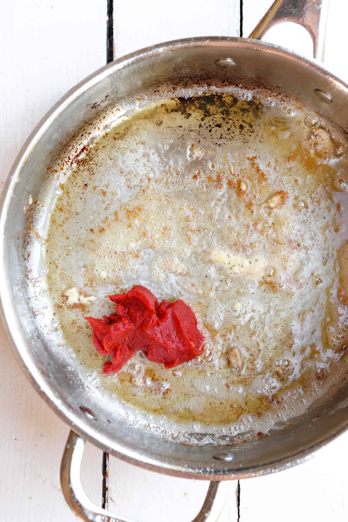 tomato paste spooned into a pan.
