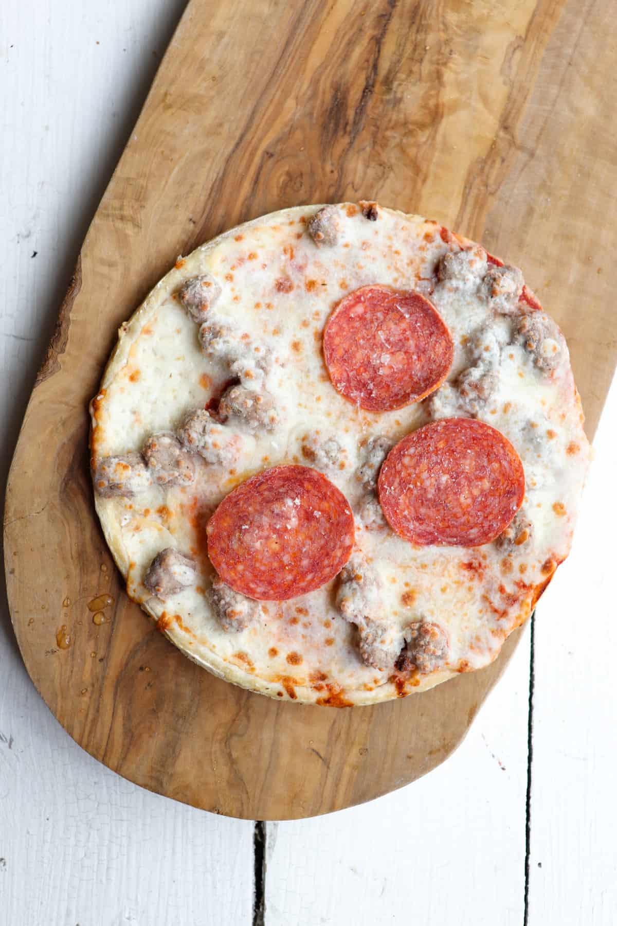 frozen personal pizza on a wooden board.
