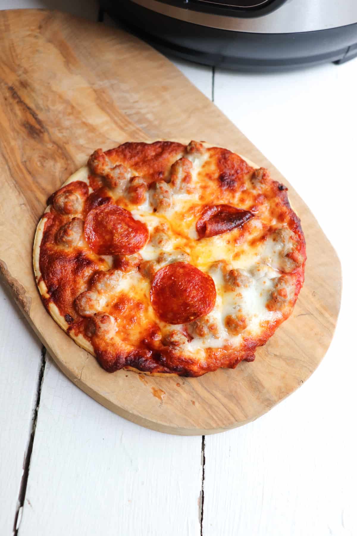 cooked mini pizza on a wooden cutting board.