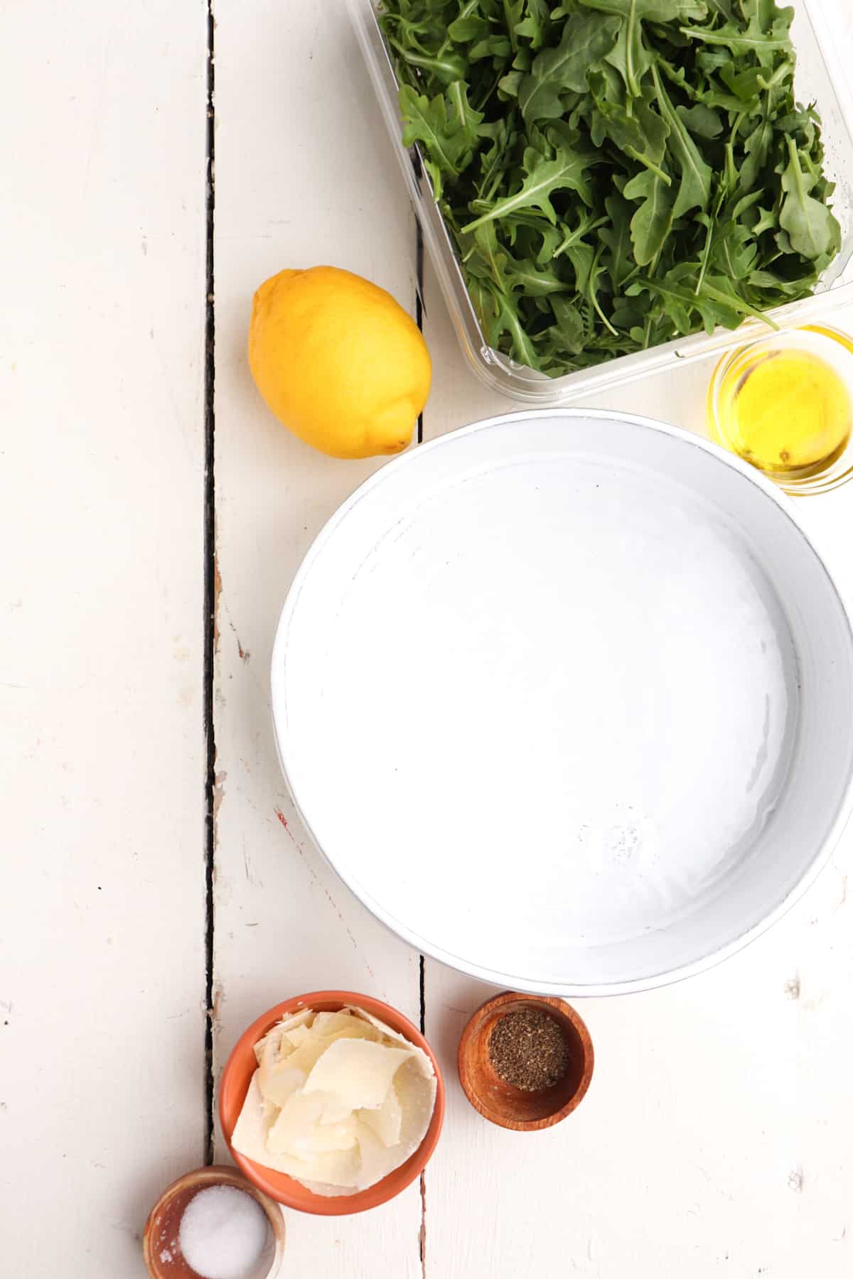 ingredients in for arugula salad with serving bowl.