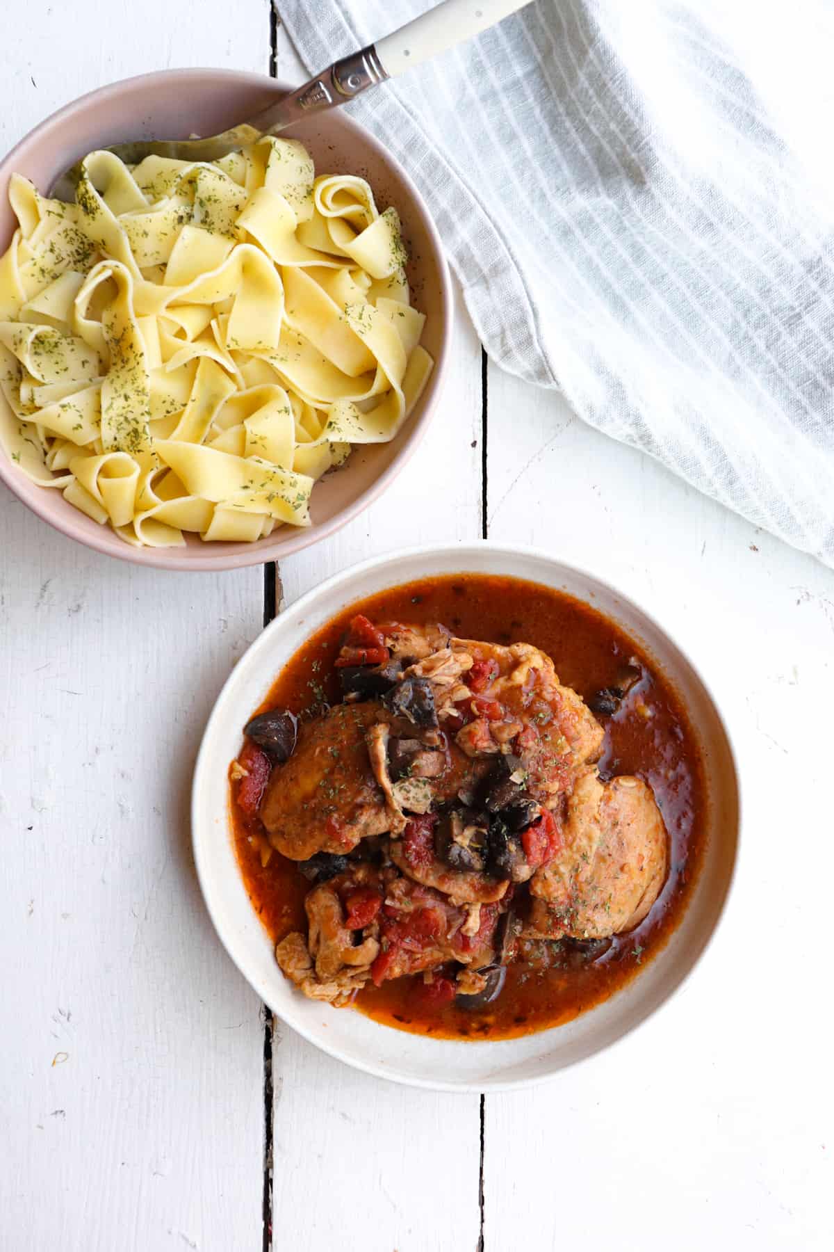 chicken chasseur on a plate with noodles to the side.