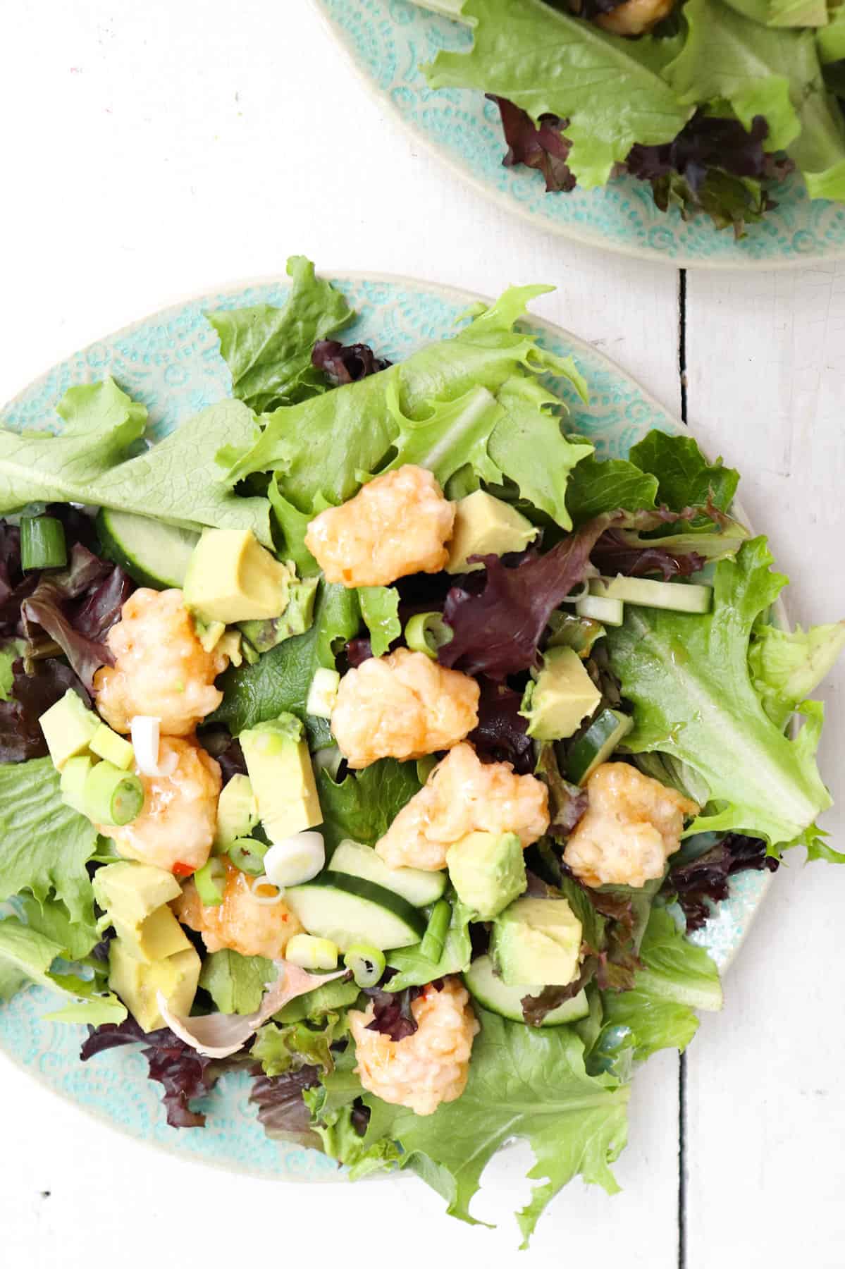 baby lettuce salad topped with tempura shrimp, avocado, and cucumber.