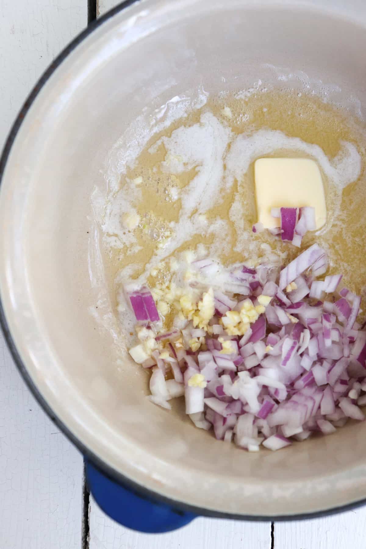 butter, shallots, and garlic, in a blue pot.