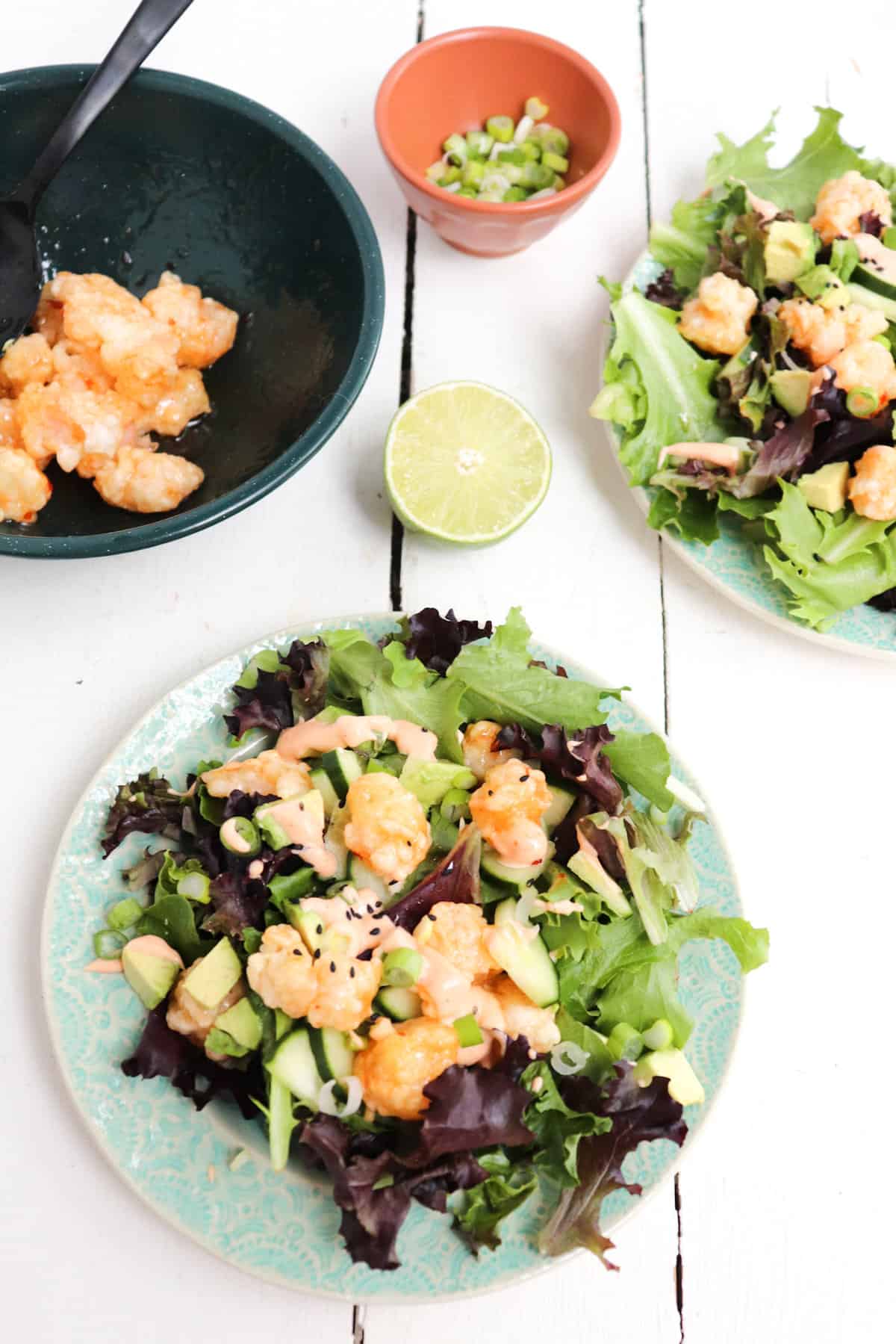 multiple bang bang shrimp salads with ingredients in background.