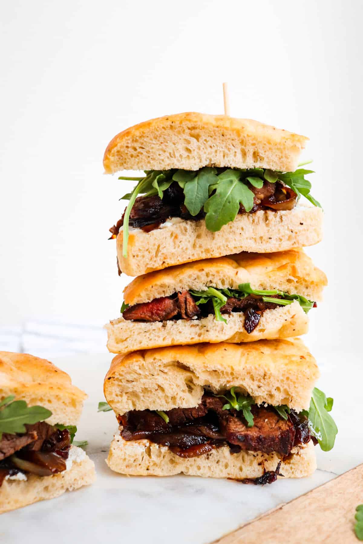 stack of steak sandwiches on a cutting board. 