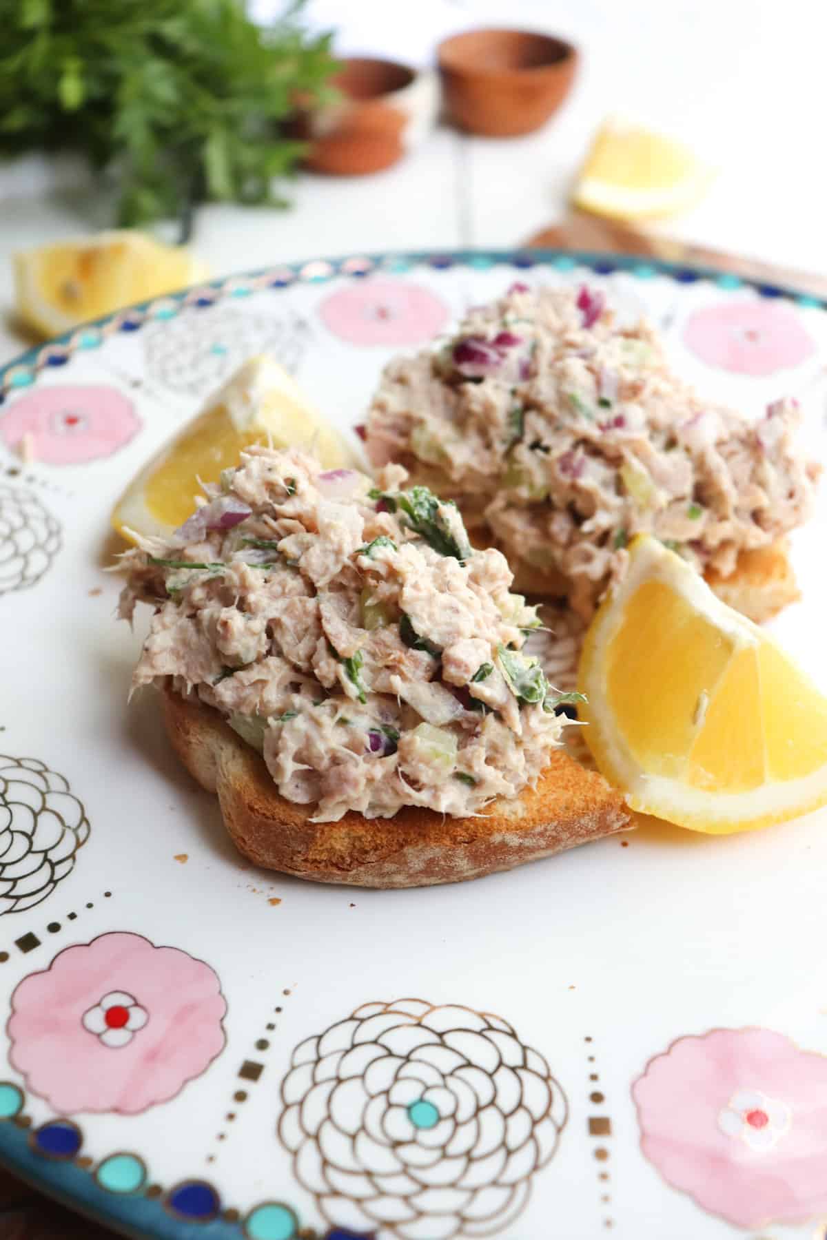 tuna on two pieces of toast with lemon wedges.
