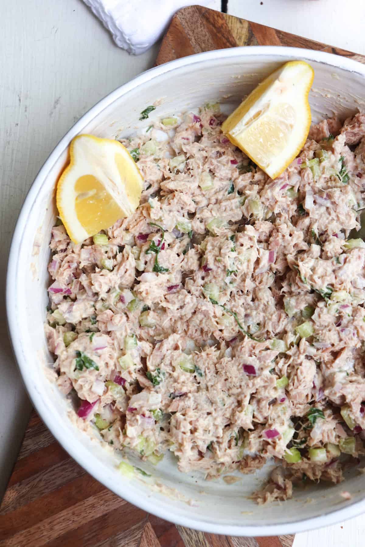tuna salad in a white bowl with lemon wedges