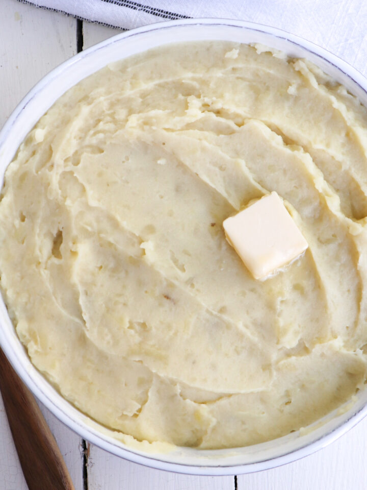 mashed potatoes in a serving dish with a black spoon.