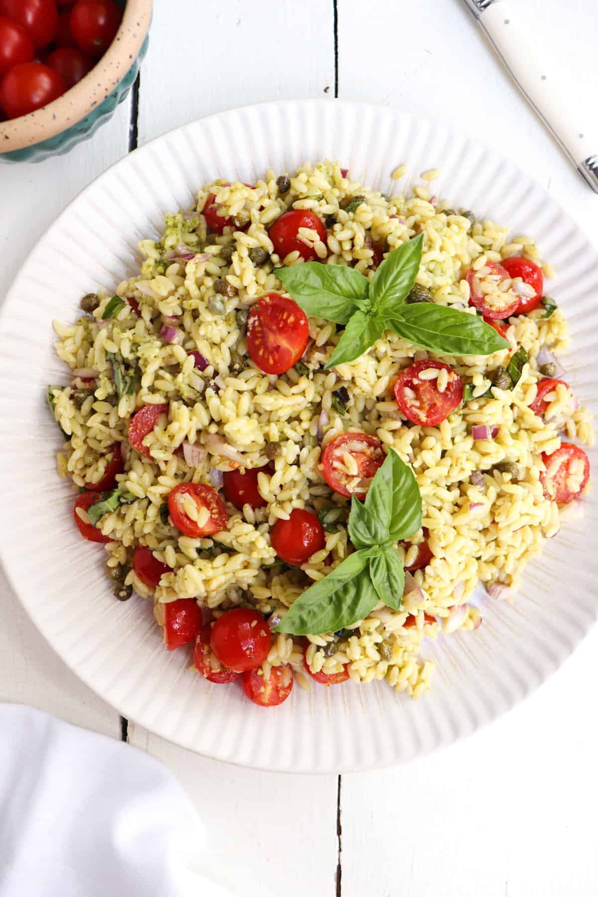 up close of pesto orzo salad garnished with basil leaves.