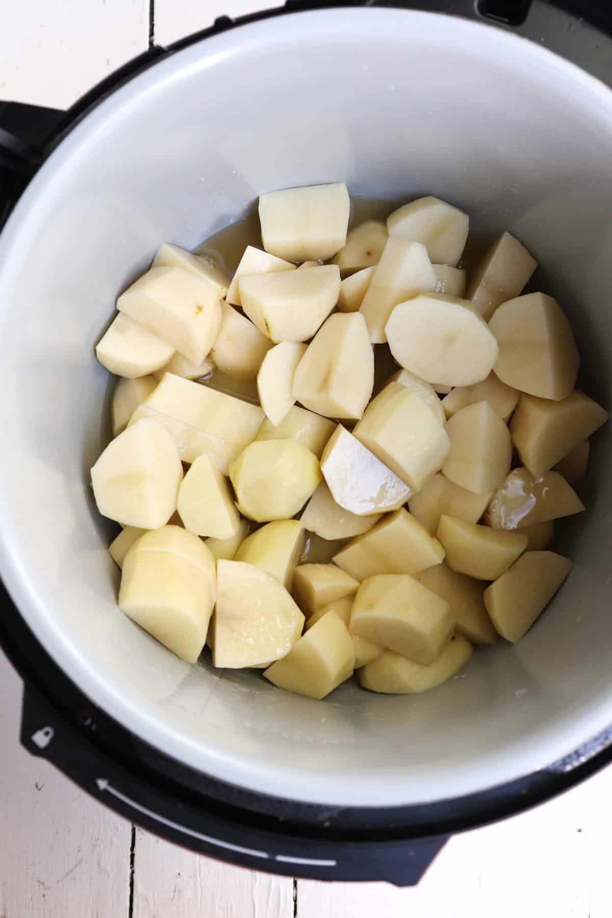 peeled and cut potatoes with stock in instant pot insert.