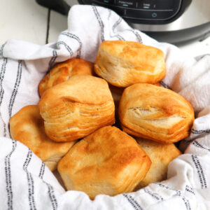 basket full of flaky biscuits with air fryer in background.