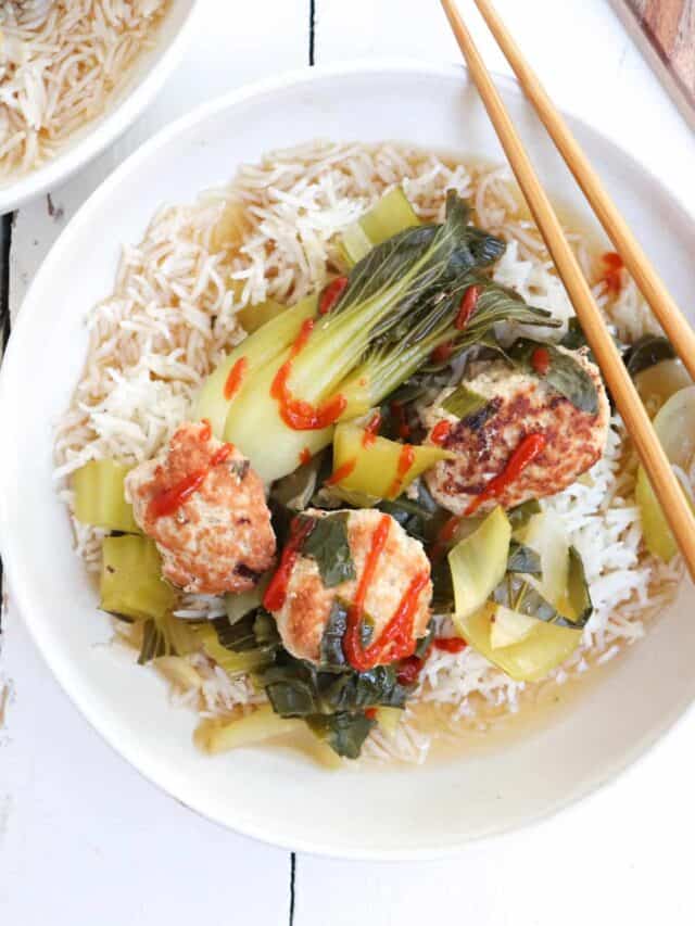 three meatballs with bok choy and rice in a bowl with chopsticks.