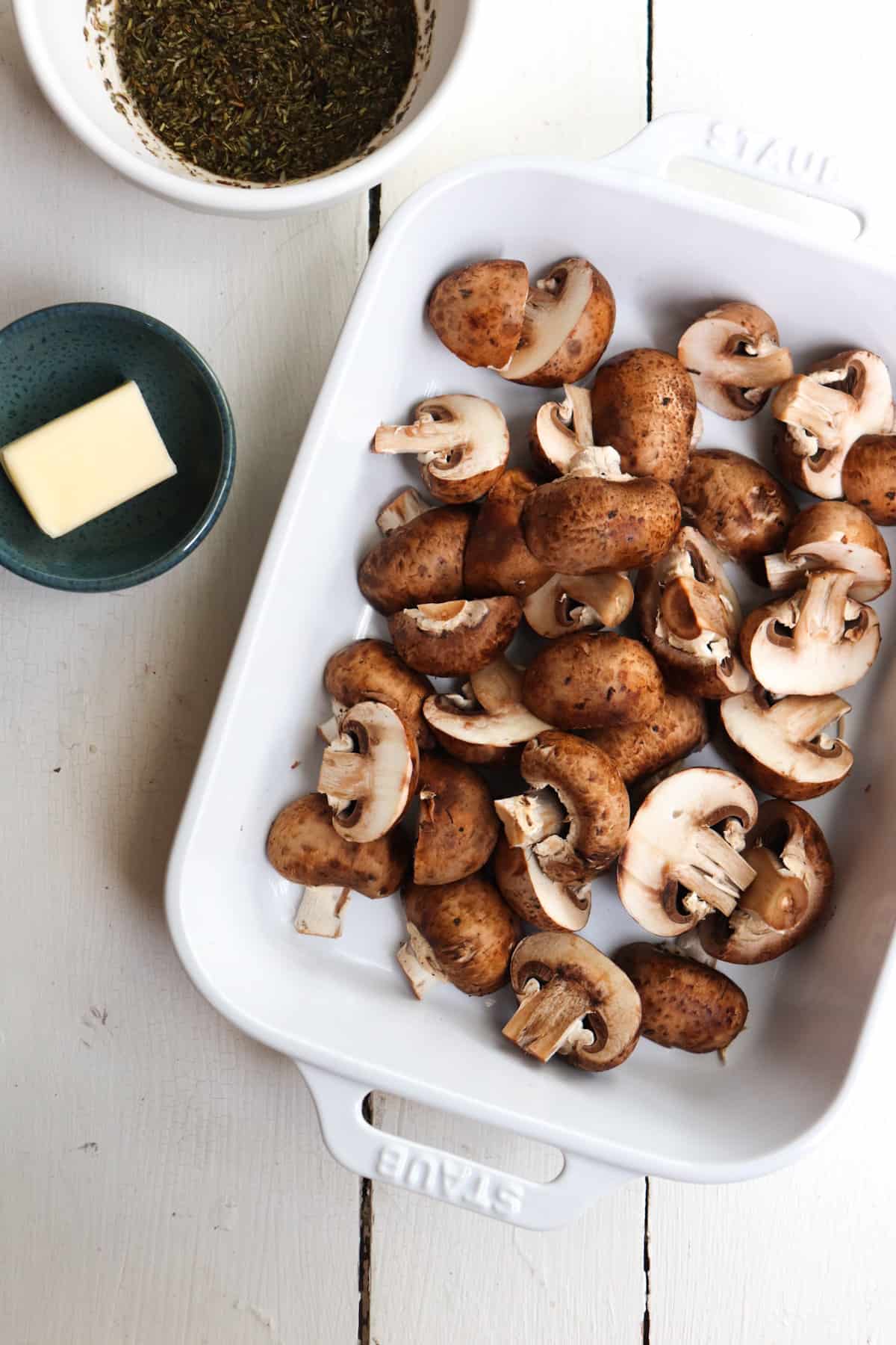 halved raw mushrooms in baking dish with sauce ingredients to the side.
