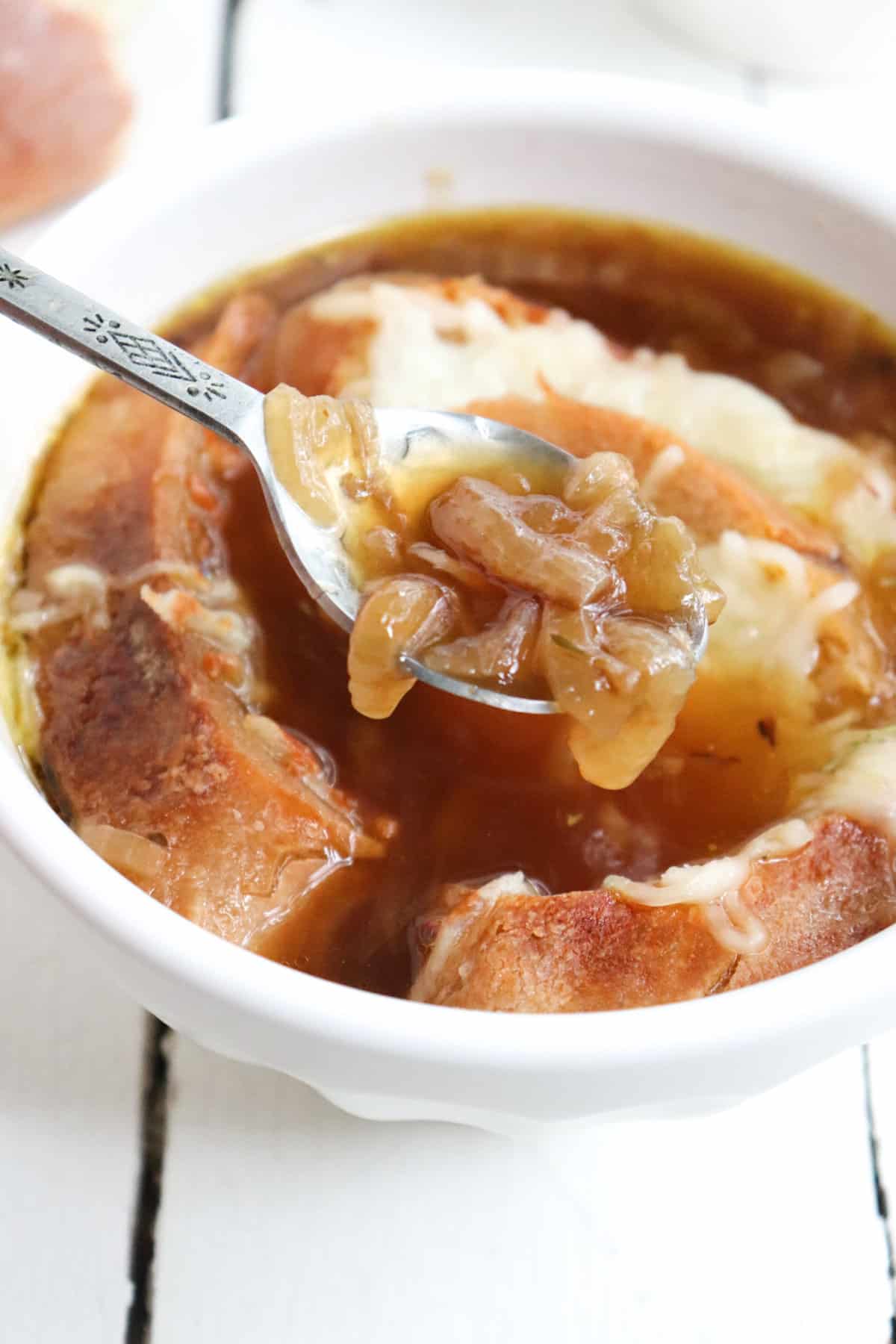 up close of onion soup on a spoon. 