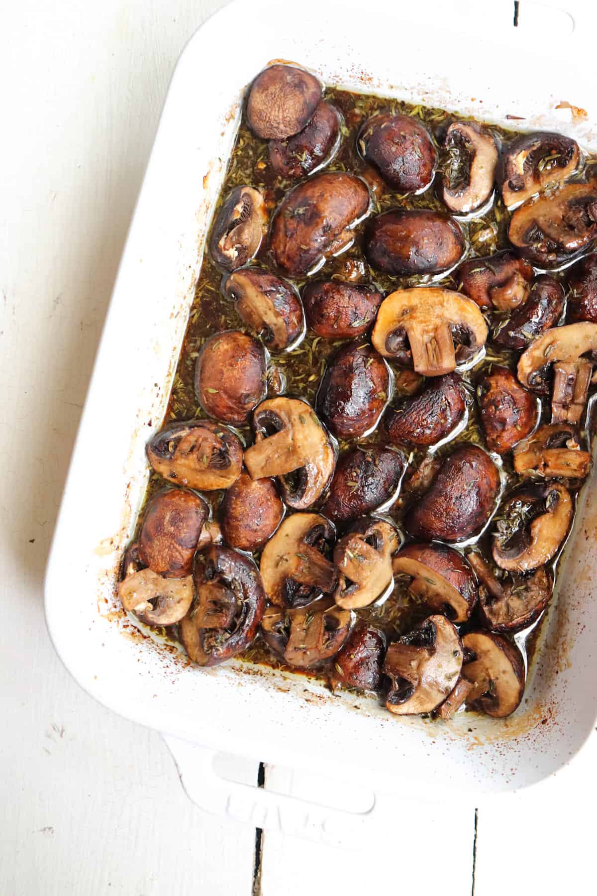 finished roasted mushrooms in a white baking dish.