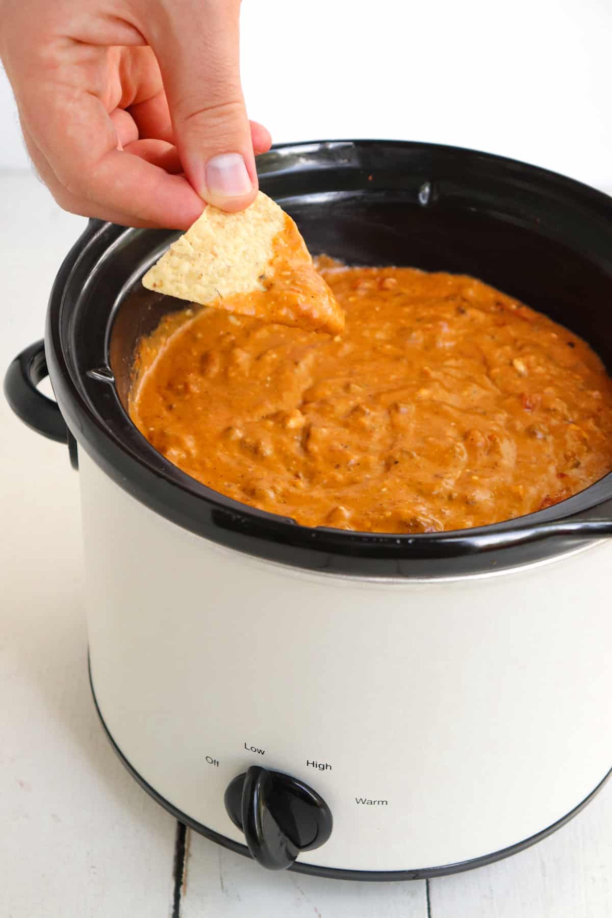 hand dipping a chip into the queso.