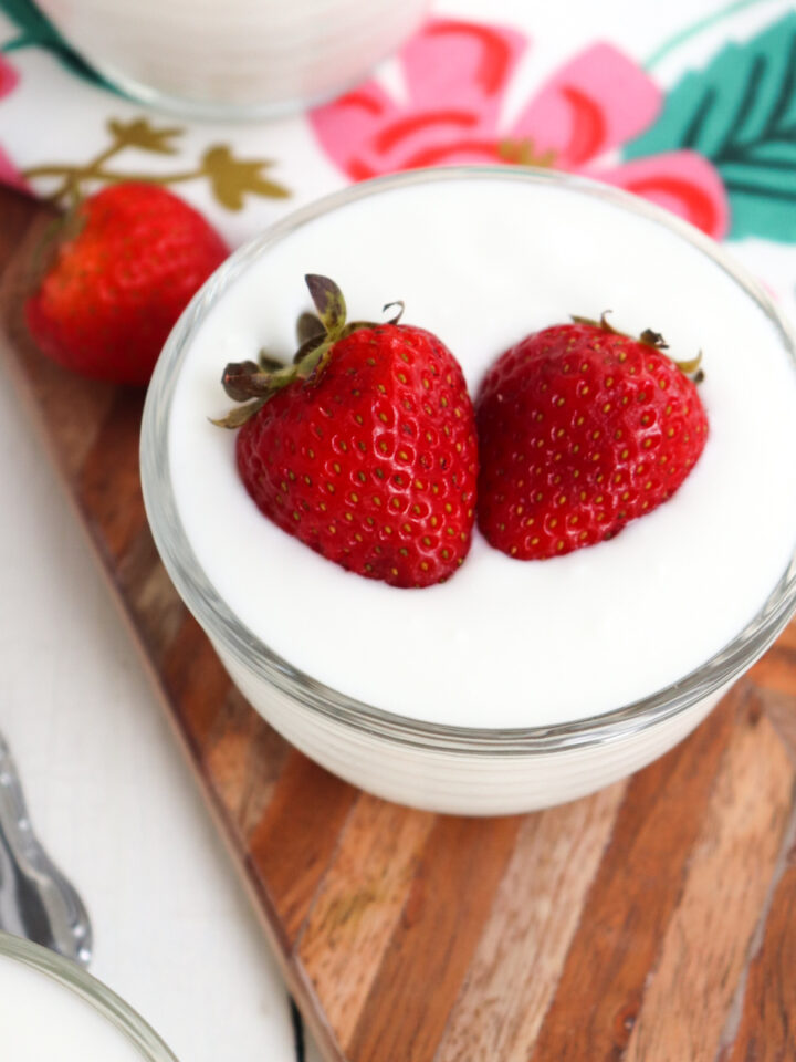 small bowl of yogurt topped with whole strawberries.