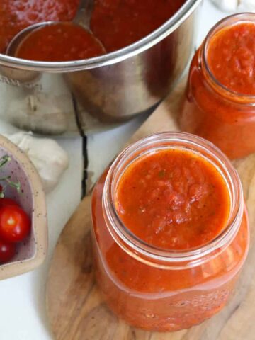 instant pot with ladle filling jars of sauce.