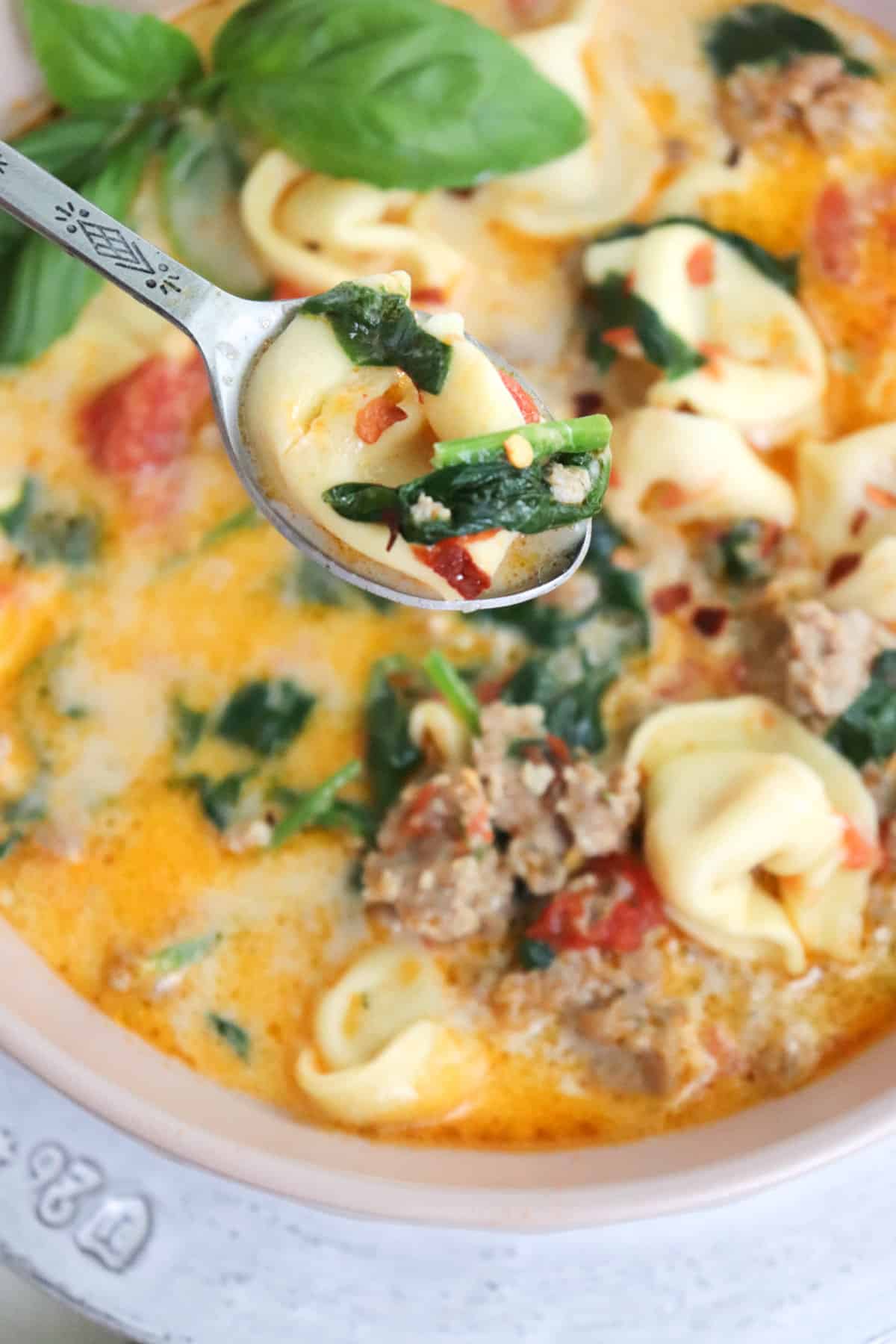 spoonful of spinach tortellini soup lifted out of bowl.