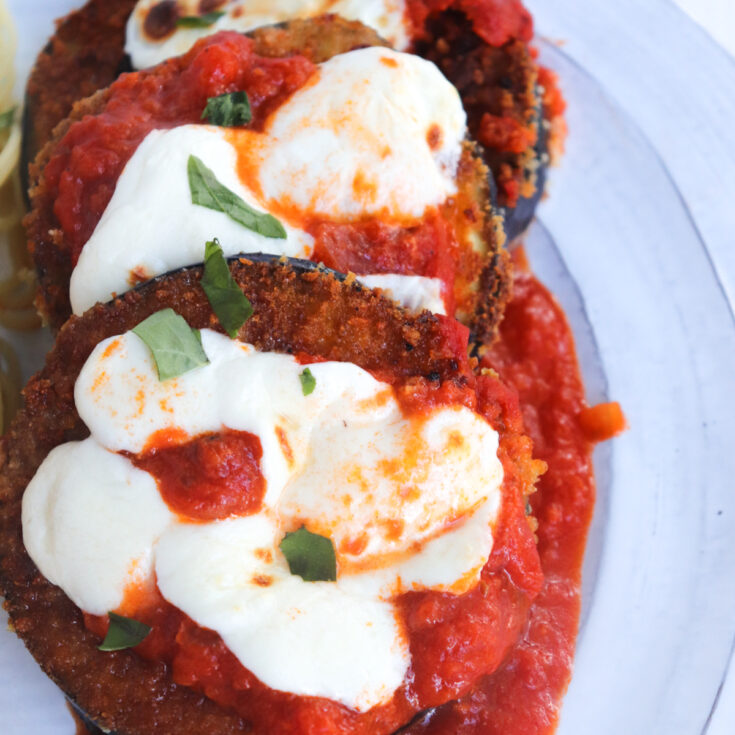 3 slices of eggplant parmigiana on a white plate.