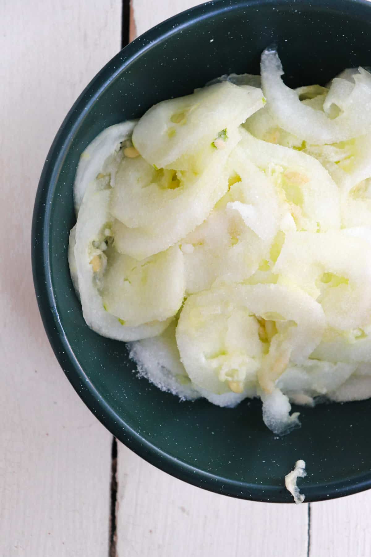 thinly sliced cucumbers covered in salt.