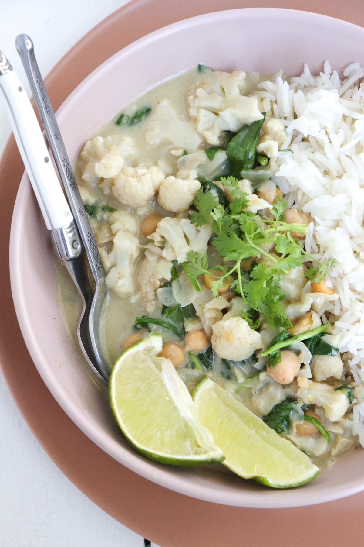 green curry with chickpeas and spinach served with limes and cilantro.