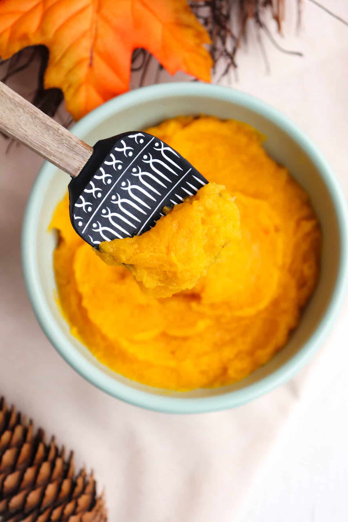spatula scooped up pumpkin puree from bowl.