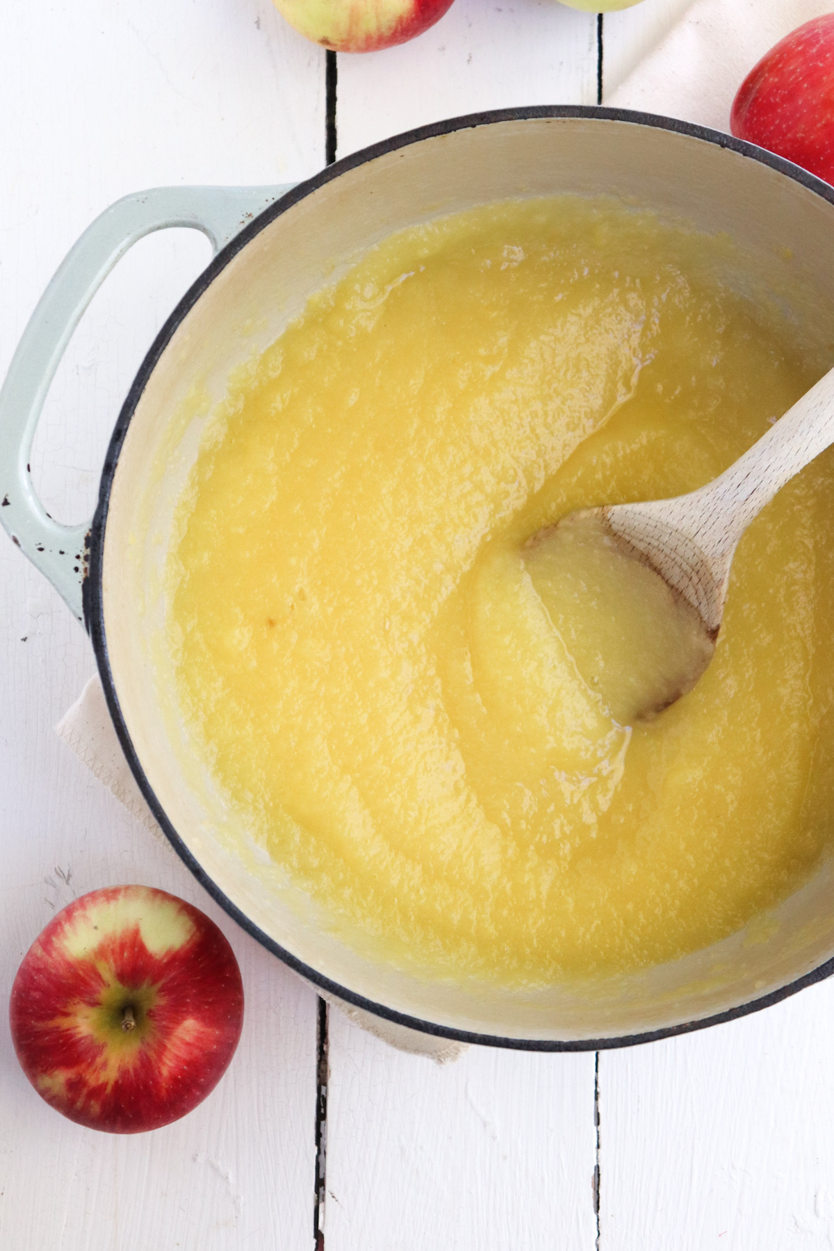 finished unsweetened applesauce being stirred with a wooden spoon.