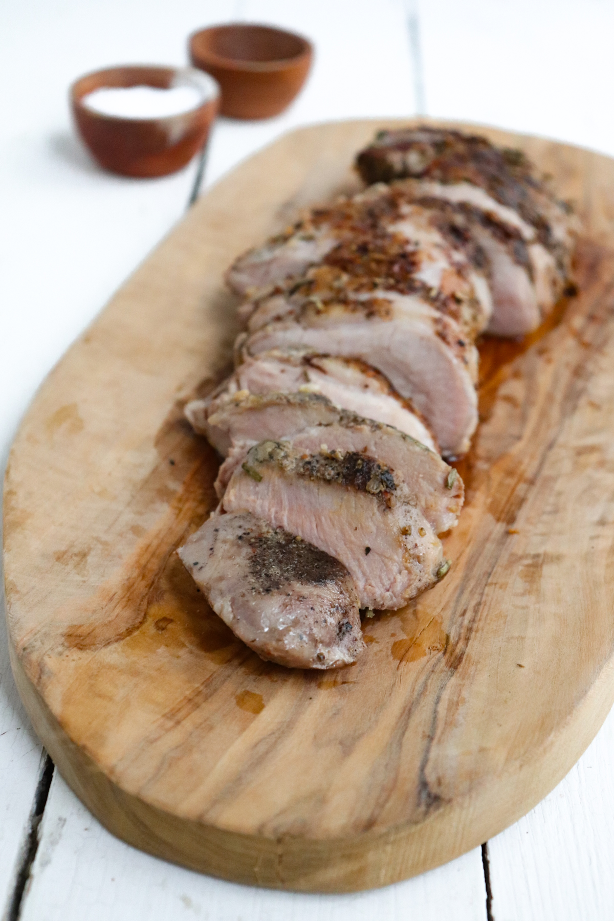 sliced pork tenderloin on a wooden cutting board.