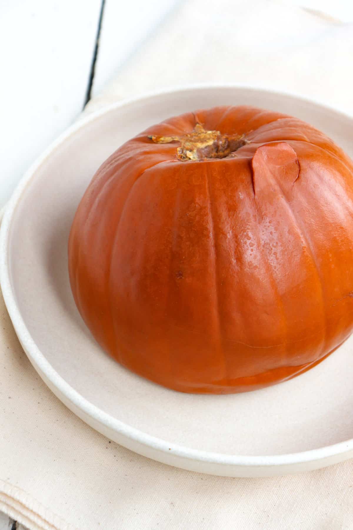 cooked whole pumpkin on a white plate.