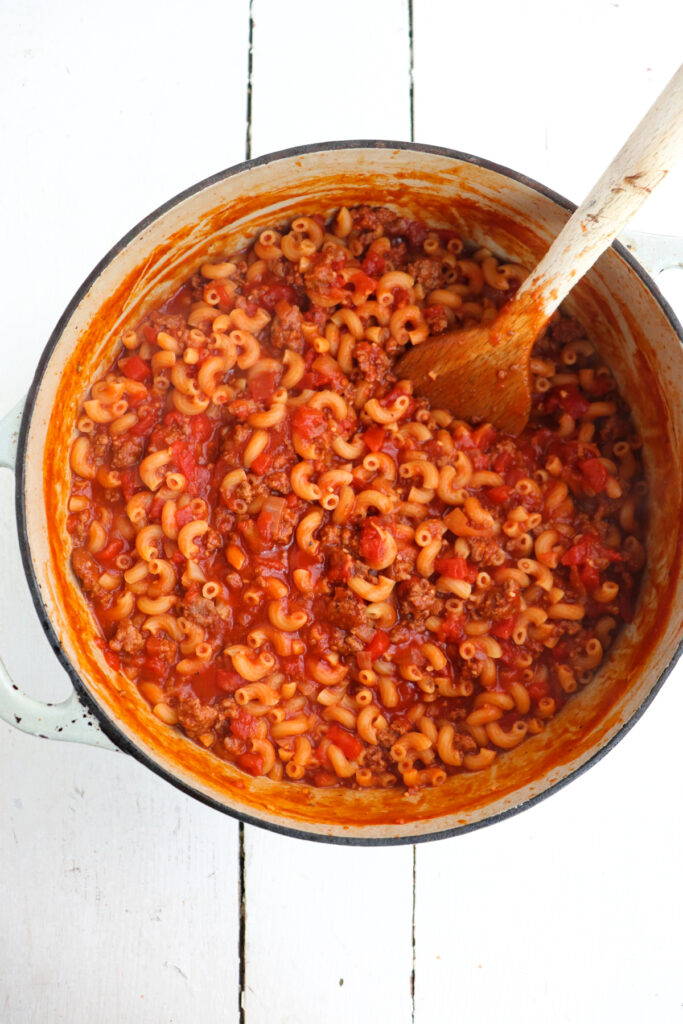 goulash in a dutch oven with a wooden spoon for stirring.