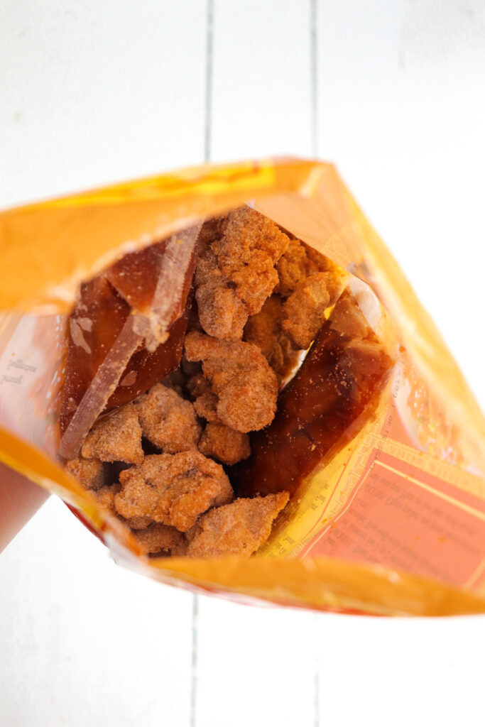 inside of bag showing frozen chicken pieces and sauce packets.