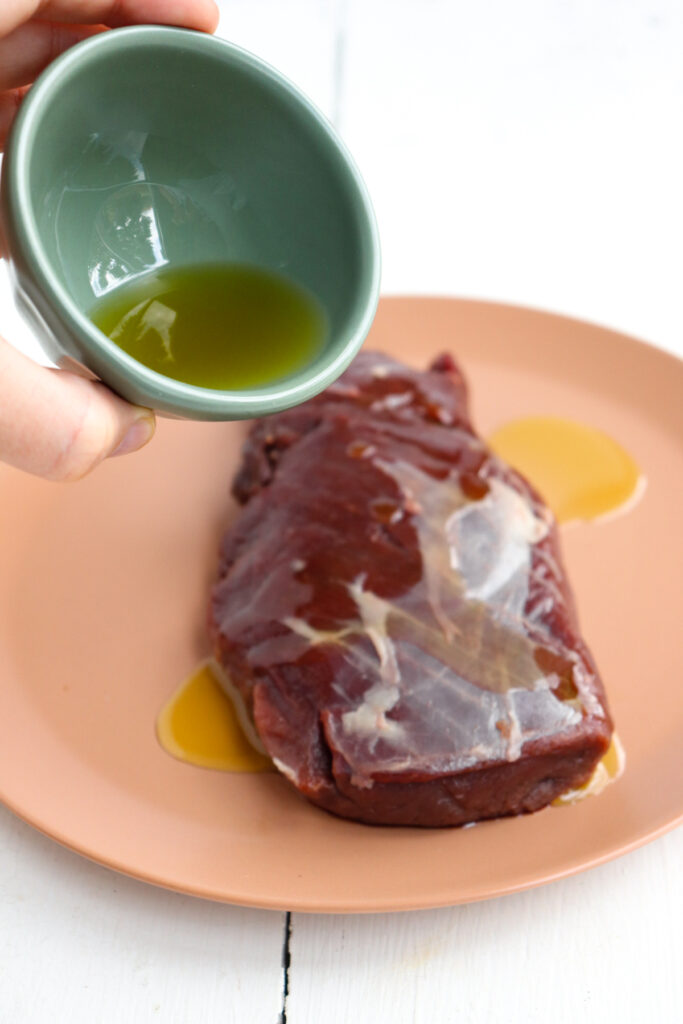 green bowl pouring oil on to meat.