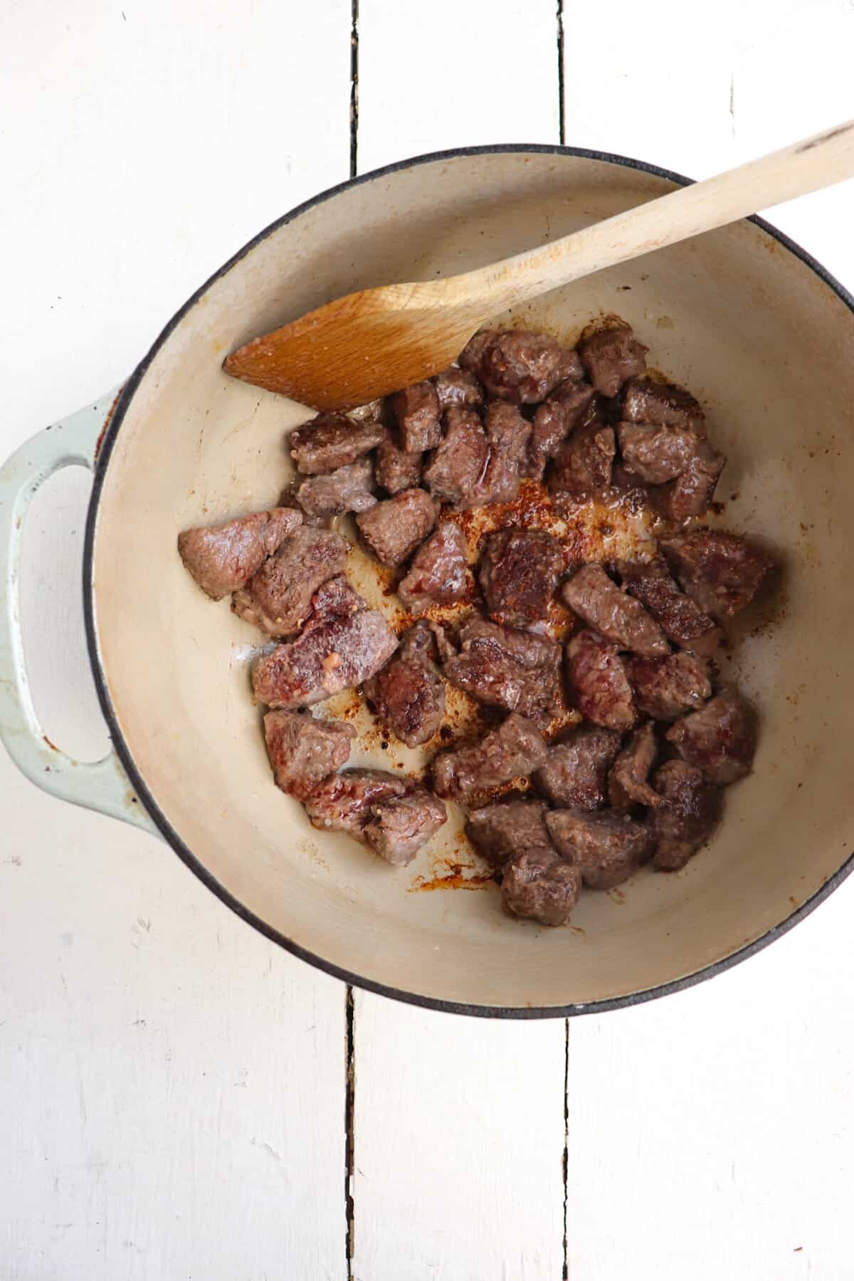 deer meat pieces being browned in the pot.